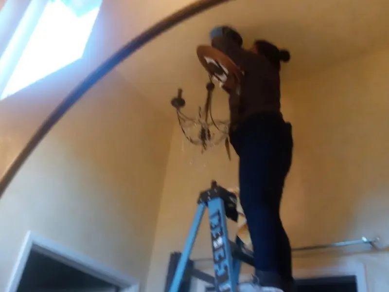 Electrician installing a chandelier in a Punxsutawney residence